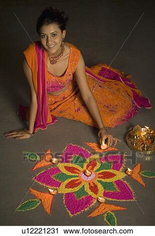 Stock Image - Portrait of a young woman making a rangoli. Fotosearch