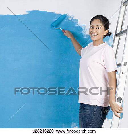 Portrait of a young woman painting a wall with a paint roller View Large Photo Image Stock Image - Portrait of a young woman painting a wall with a paint roller. Fotosearch