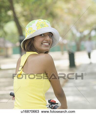 Stock Image - Portrait of a young woman riding a bicycle and smiling. Fotosearch