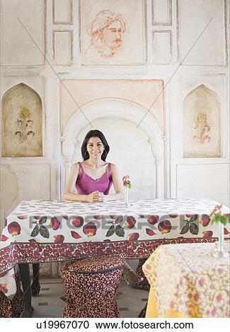 Stock Image - Portrait of a young woman sitting in a restaurant and smiling. Fotosearch