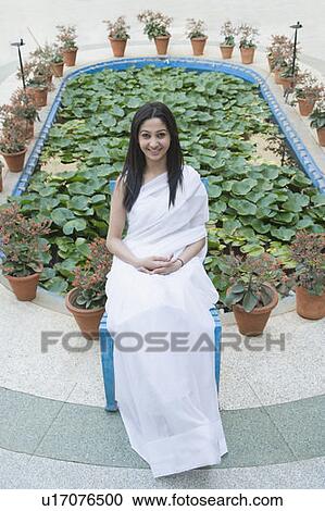 Portrait of a young woman sitting on a stool and smiling View Large Photo Image Stock Image - Portrait of a young woman sitting on a stool and smiling. Fotosearch