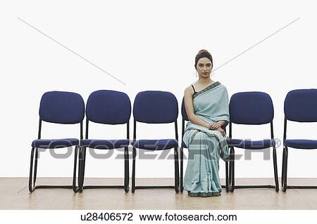 Portrait of a young woman sitting on a chair View Large Photo Image Stock Image - Portrait of a young woman sitting on a chair. Fotosearch