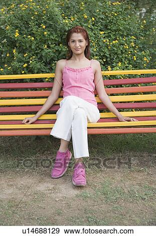 Stock Photo - Portrait of a young woman sitting on a bench. Fotosearch