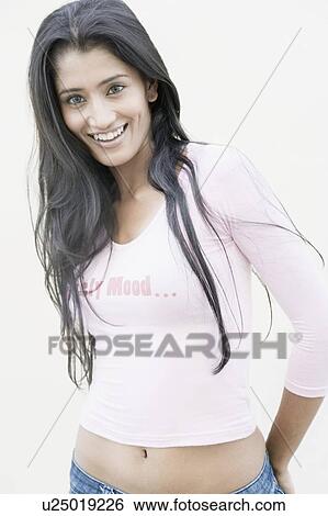 Stock Photograph - Portrait of a young woman standing and smiling. Fotosearch