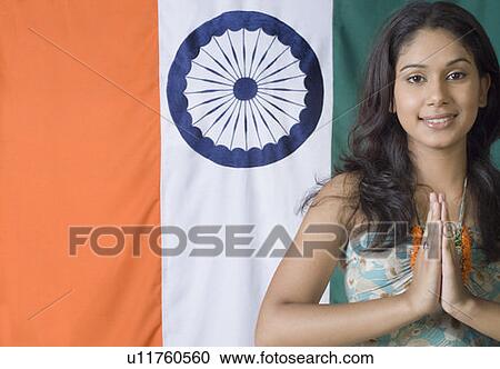 Stock Image - Portrait of a young woman standing in front of an Indian flag. Fotosearch