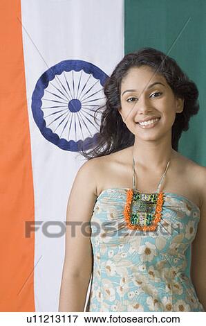 Stock Photo - Portrait of a young woman standing in front of an Indian flag. Fotosearch