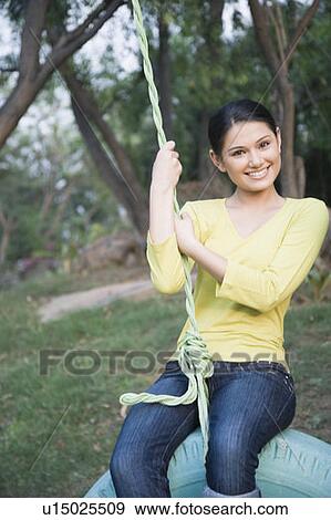 Portrait of a young woman swinging on a tire swing View Large Photo Image Stock Photo - Portrait of a young woman swinging on a tire swing. Fotosearch