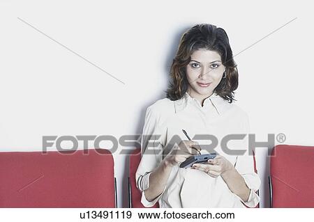 Stock Photo - Portrait of a young woman using a personal data assistant. Fotosearch