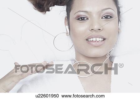 Stock Image - Portrait of a young woman wearing earphones listening to music. Fotosearch