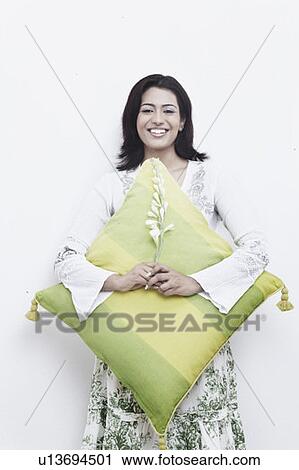 Portrait of a young woman with a flower in her hand hugging a cushion View Large Photo Image Stock Image - Portrait of a young woman with a flower in her hand hugging a cushion. Fotosearch