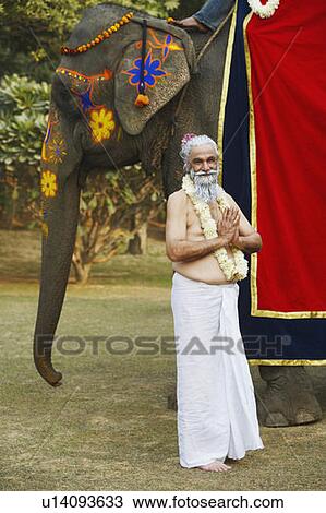Priest standing beside an elephant View Large Photo Image Stock Image - Priest standing beside an elephant. Fotosearch