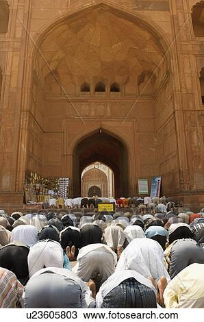 Stock Image - Rear view of a group of people praying in a mosque. Fotosearch