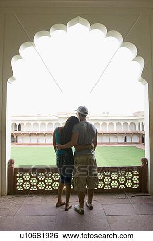 Stock Photograph - Rear view of a young couple standing with their arms around each other, Taj Mahal, Agra, Uttar Pradesh, India. Fotosearch