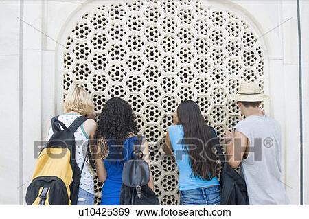 Stock Photo - Rear view of a young man and three young women looking through a window, Taj Mahal, Agra, Uttar Pradesh, India. Fotosearch
