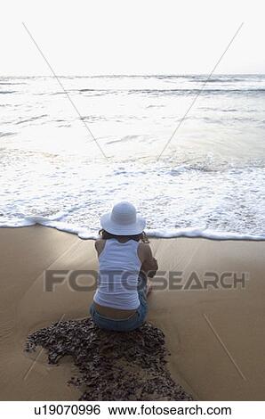 Rear view of a young woman sitting on the beach, Goa, India View Large Photo Image Stock Photograph - Rear view of a young woman sitting on the beach, Goa, India. Fotosearch