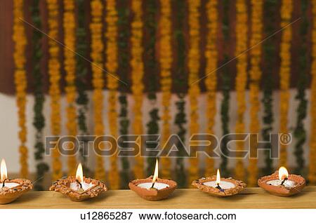 Stock Photo - Row of burning traditional diwali lamps. Fotosearch