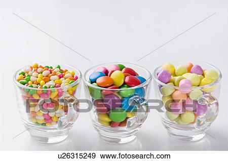 Stock Photo - Row of three cups filled with jellybeans and candies. Fotosearch