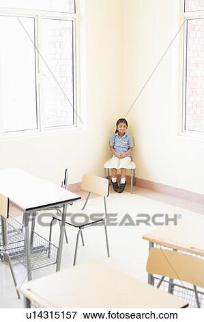 Stock Photo - Schoolgirl sitting on a chair in a classroom. Fotosearch