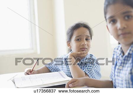 Schoolgirls sitting at a desk with her hand on her chin View Large Photo Image Stock Photo - Schoolgirls sitting at a desk with her hand on her chin. Fotosearch