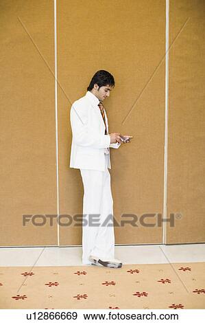 Stock Photo - Side profile of a businessman using a mobile phone. Fotosearch