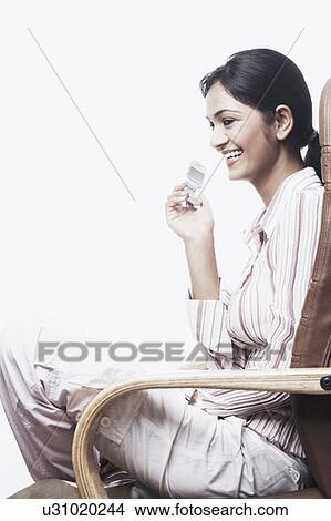 Picture - Side profile of a businesswoman sitting on a chair with her legs crossed. Fotosearch