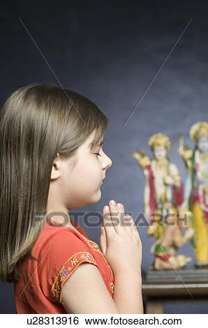 Side profile of a girl praying in front of statues of God View Large Photo Image Stock Photograph - Side profile of a girl praying in front of statues of God. Fotosearch