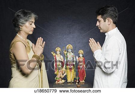 Side profile of a mature woman with her son praying in front of statues of God View Large Photo Image Stock Photo - Side profile of a mature woman with her son praying in front of statues of God. Fotosearch