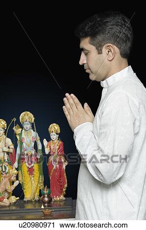 Side profile of a mid adult man praying in front of figurines of God View Large Photo Image Stock Image - Side profile of a mid adult man praying in front of figurines of God. Fotosearch