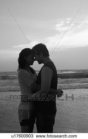 Side profile of a young couple embracing each other on the beach View Large Photo Image Stock Image - Side profile of a young couple embracing each other on the beach. Fotosearch