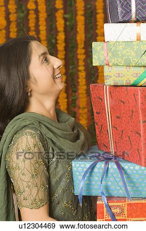 Side profile of a young woman holding a gift View Large Photo Image Stock Photo - Side profile of a young woman holding a gift. Fotosearch