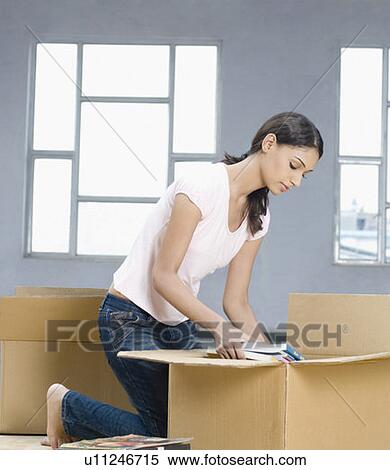 Side profile of a young woman packing a cardboard box View Large Photo Image Stock Photography - Side profile of a young woman packing a cardboard box. Fotosearch