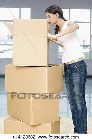 Side profile of a young woman peeking into a cardboard box View Large Photo Image Stock Image - Side profile of a young woman peeking into a cardboard box. Fotosearch