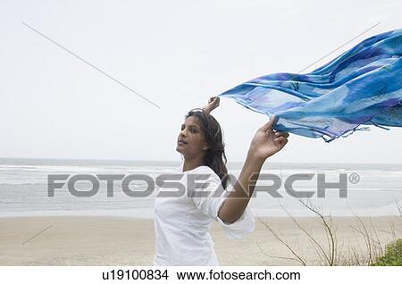 Side profile of a young woman running with her shawl on the beach View Large Photo Image Picture - Side profile of a young woman running with her shawl on the beach. Fotosearch
