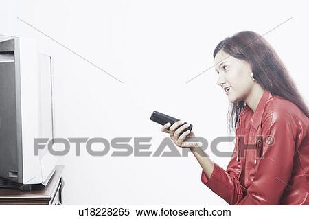 Stock Photography - Side profile of a young woman watching television. Fotosearch