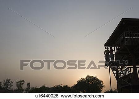 Stock Photograph - Silhouette of a man and a woman standing in a log cabin. Fotosearch