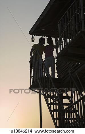 Picture - Silhouette of a young couple standing on the beach hut. Fotosearch