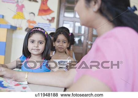 Teacher checking drawings of students in a classroom View Large Photo Image Stock Photo - Teacher checking drawings of students in a classroom. Fotosearch