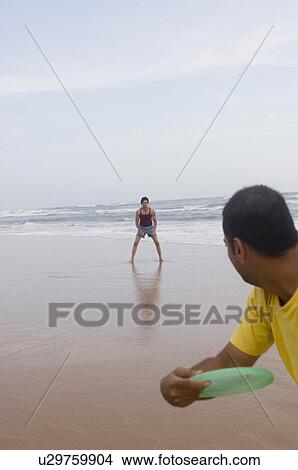 Two young men playing with a plastic disc on the beach View Large Photo Image Picture - Two young men playing with a plastic disc on the beach. Fotosearch