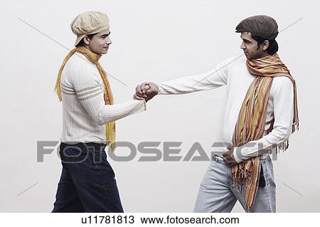 Two young men shaking hands View Large Photo Image Stock Image - Two young men shaking hands. Fotosearch