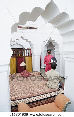 Stock Photo - Waiter holding a teapot in a tray in front of a man. Fotosearch