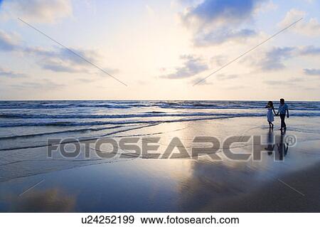 Young couple holding each other's hands and walking on the beach View Large Photo Image Stock Photo - Young couple holding each other's hands and walking on the beach. Fotosearch