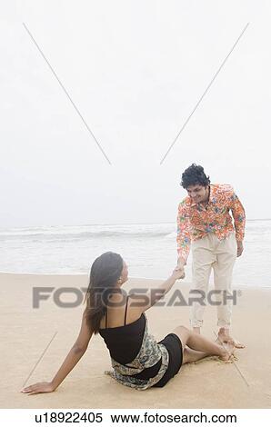 Stock Photography - Young couple looking at each other and smiling on the beach. Fotosearch