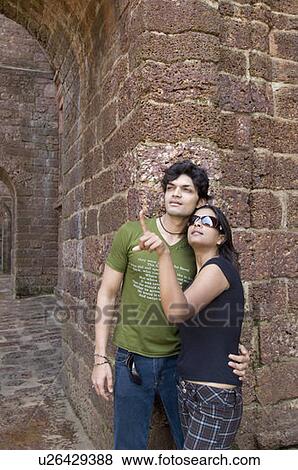 Stock Photo - Young couple standing in front of a wall, Goa, India. Fotosearch