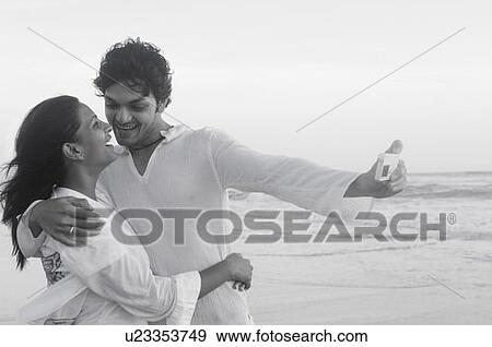 Stock Photo - Young couple taking a photograph themselves with a digital camera on the beach. Fotosearch