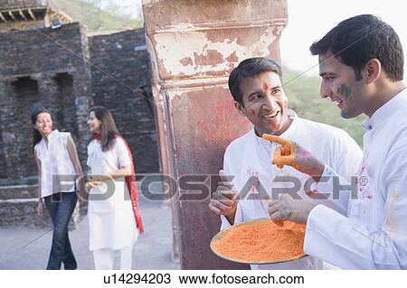 Young man and a mid adult man hiding behind a column and waiting for two women View Large Photo Image Stock Image - Young man and a mid adult man hiding behind a column and waiting for two women. Fotosearch