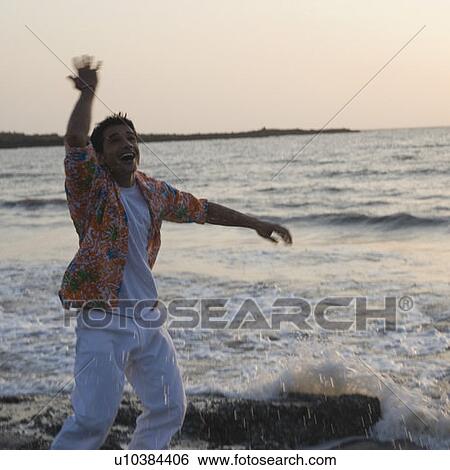Stock Photograph - Young man dancing on the coast. Fotosearch