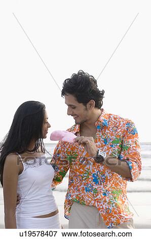 Stock Photo - Young man offering a cotton candy to a young woman. Fotosearch