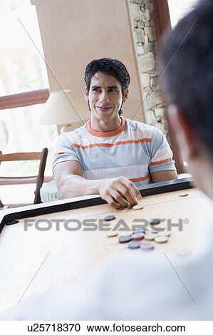 Stock Image - Young man playing carom. Fotosearch