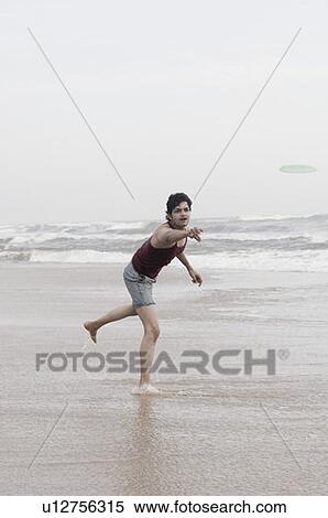 Young man playing with a plastic disc on the beach View Large Photo Image Stock Photography - Young man playing with a plastic disc on the beach. Fotosearch