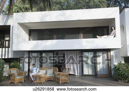 Stock Photo - Young man sitting on a couch in front of a building. Fotosearch